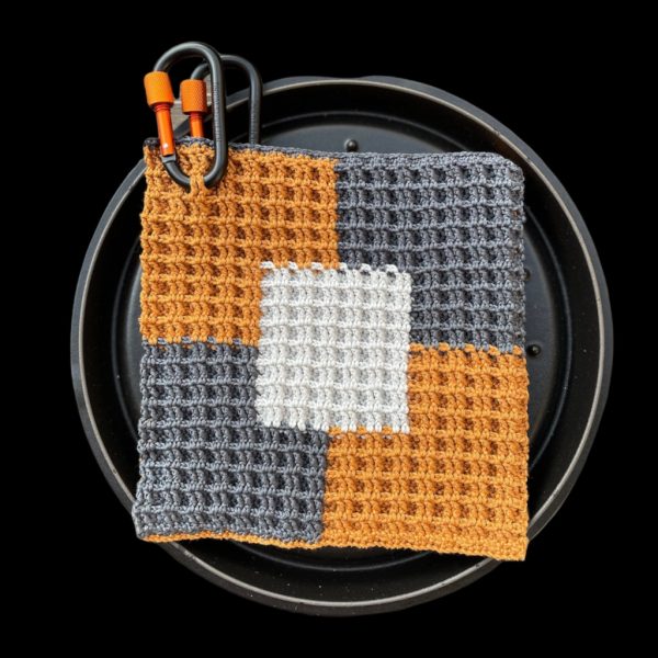 Handgemachte gehäkelte Topflappen online kaufen im Patchwork-Design in Grau, Weiß und Rostbraun, dekorativ zwischen frischem Gemüse arrangiert